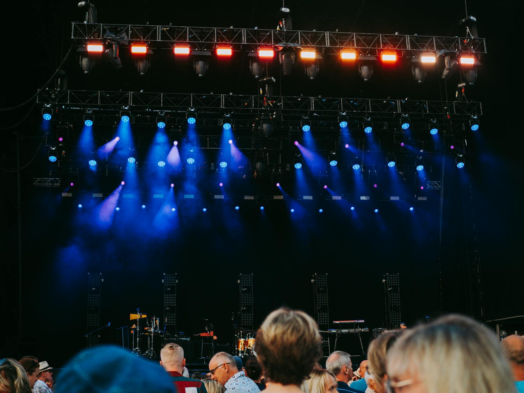 A crowd at a night concert with stage lights at a motorsport event