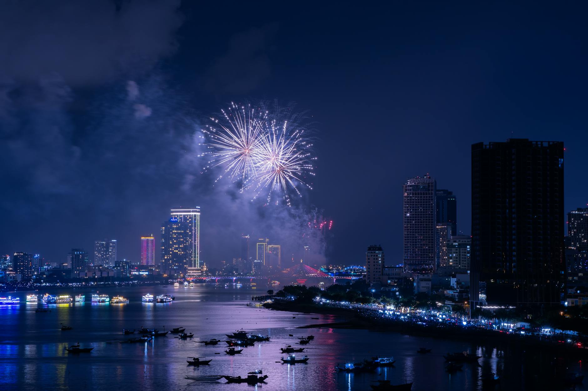 New Year's Eve fireworks bursting over a city river at night