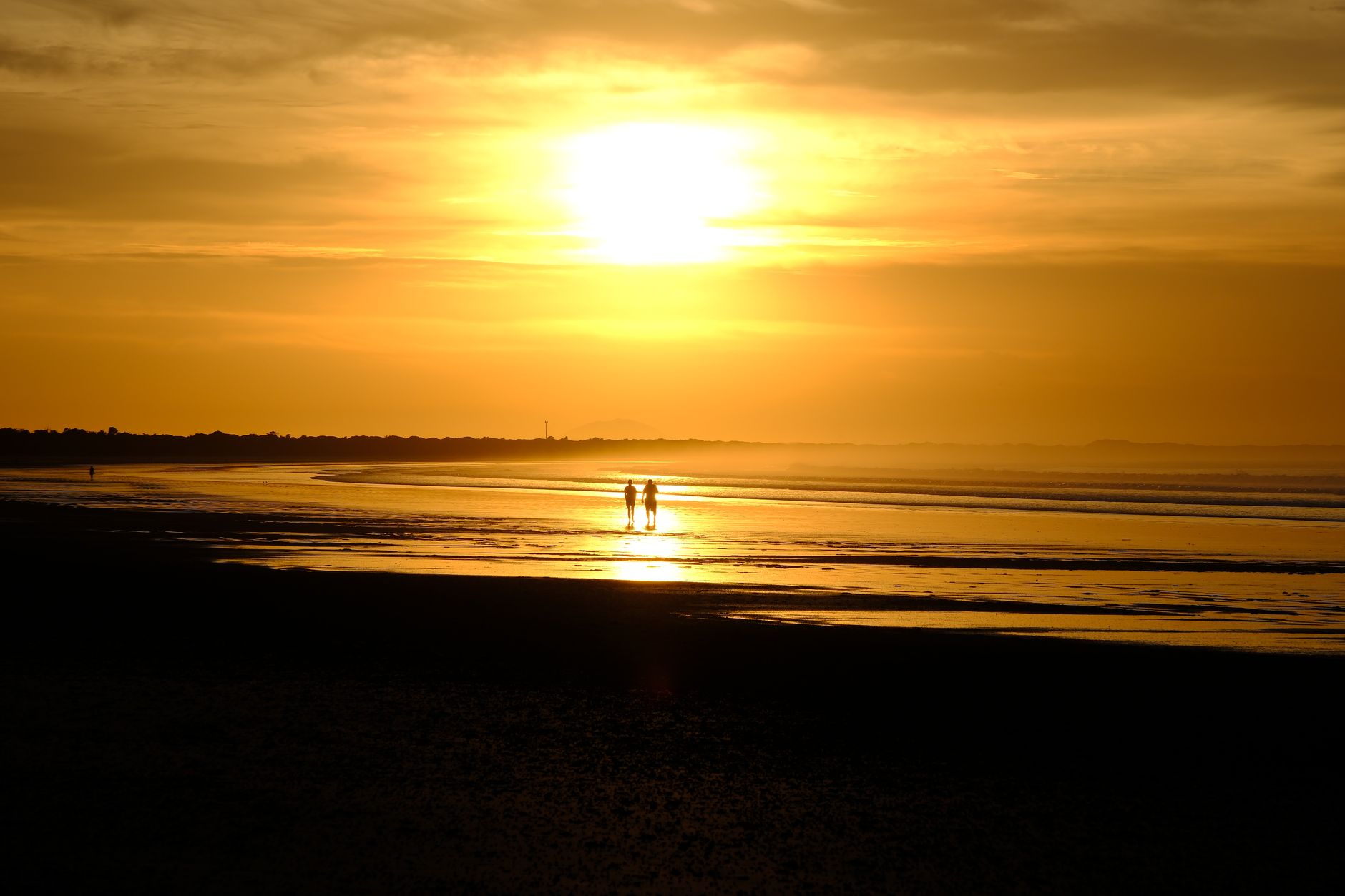 A couple walking a beach at sunset near Adelaide