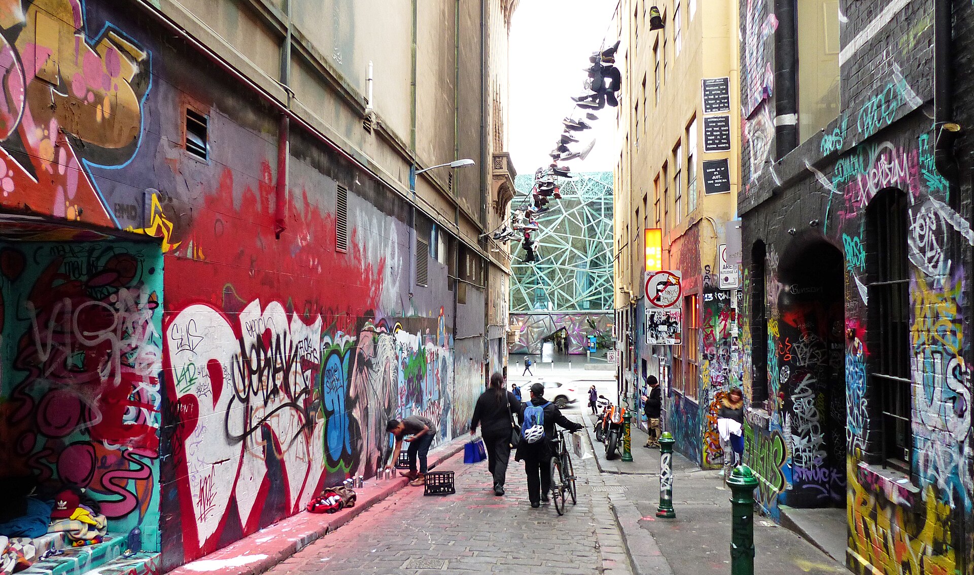 Street art covering the walls of Hosier Lane in Melbourne with pedestrians walking through