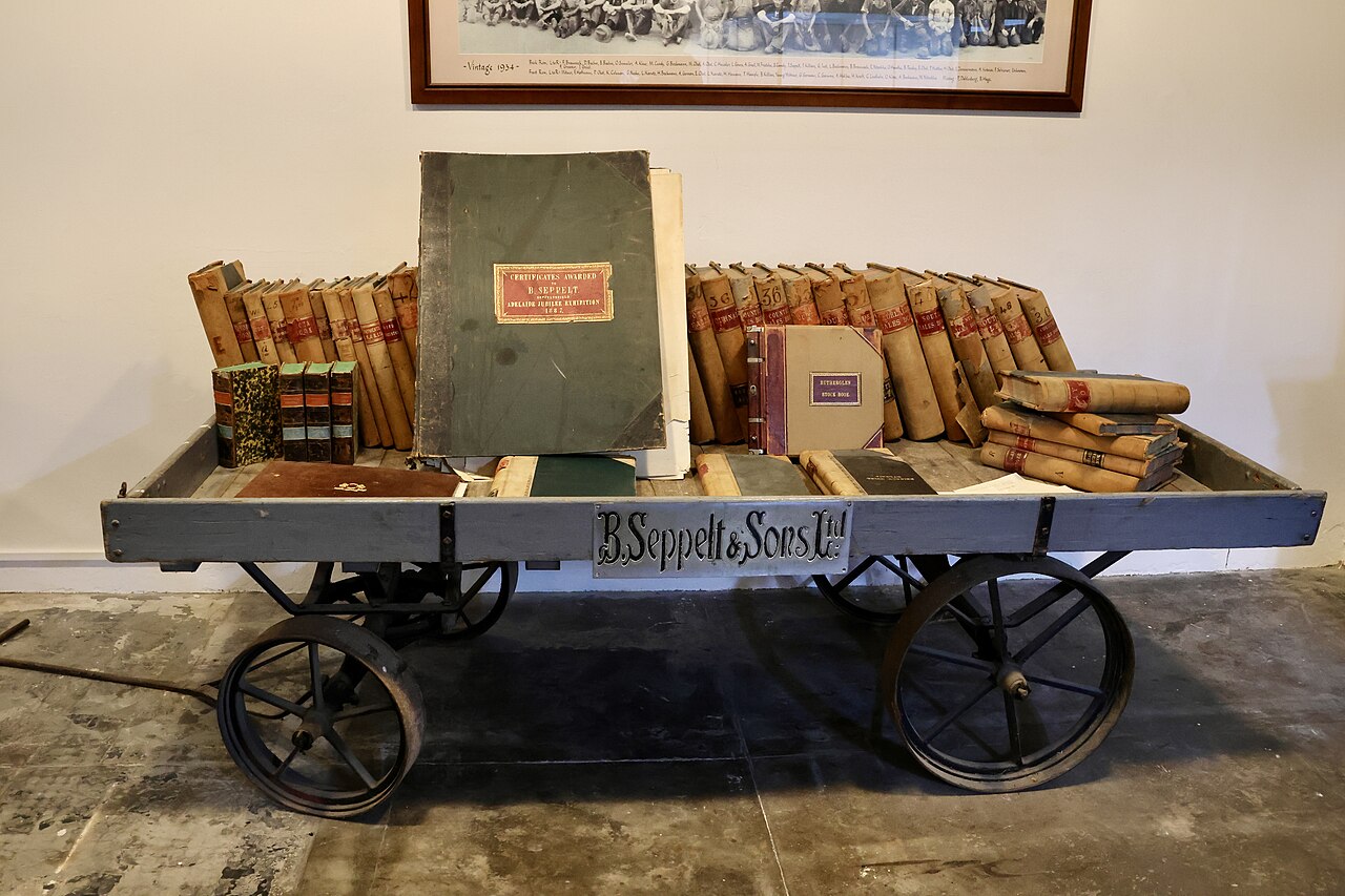 Old leather-bound ledgers and account books stacked on a wooden trolley stencilled B. Seppelt and Sons Ltd