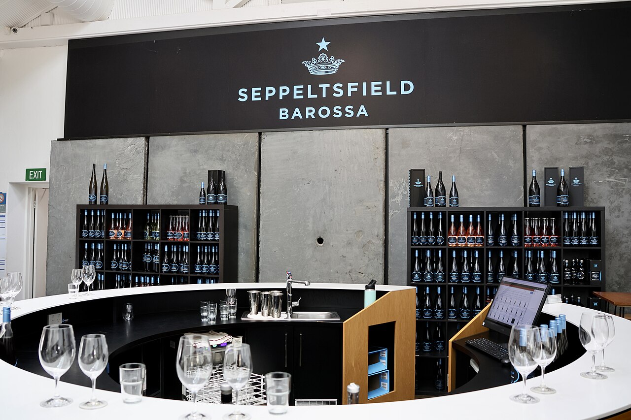 The modern Seppeltsfield Barossa cellar door with a curved white tasting bar, wine glasses and shelves of bottles under the Seppeltsfield sign