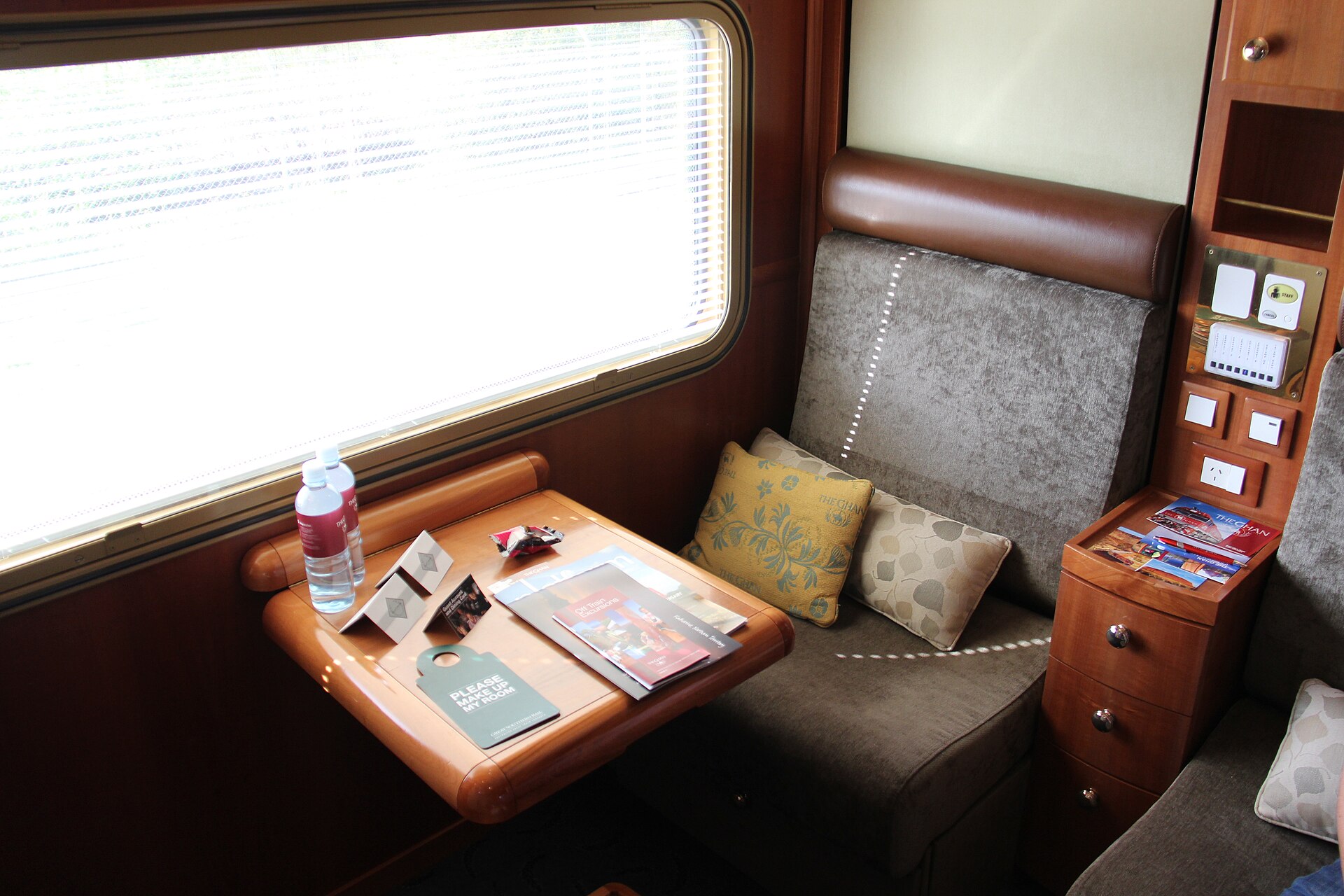 A timber-panelled sleeper cabin on The Ghan with a fold-down table beside the window