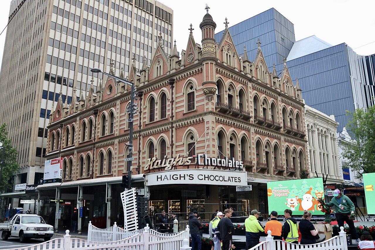 The ornate red Beehive Corner building at the corner of Rundle Mall and King William Street, with Haigh's Chocolates on the ground floor and white barriers set up for the Christmas Pageant