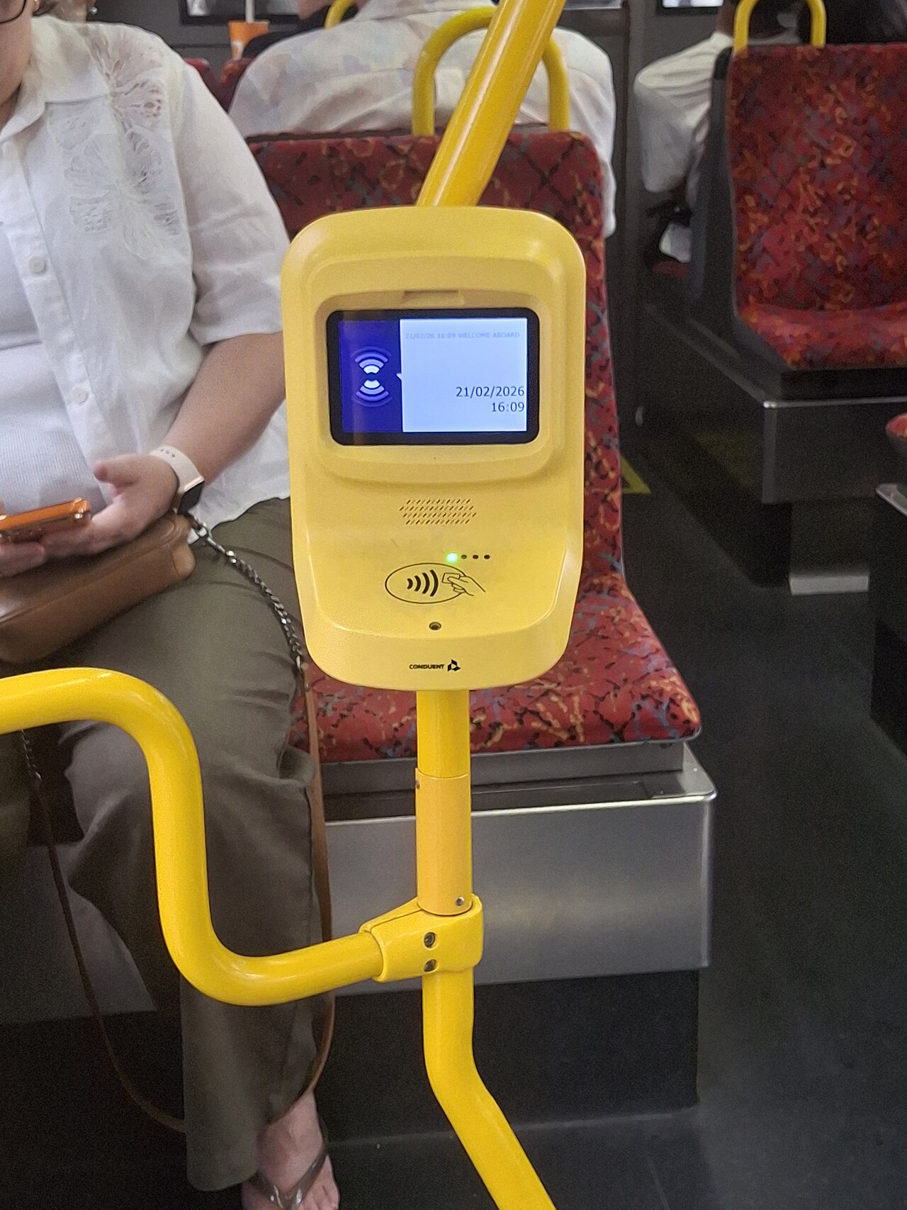 A yellow Adelaide Metro smart validator with a small screen and contactless symbol, mounted on a grab pole inside a bus