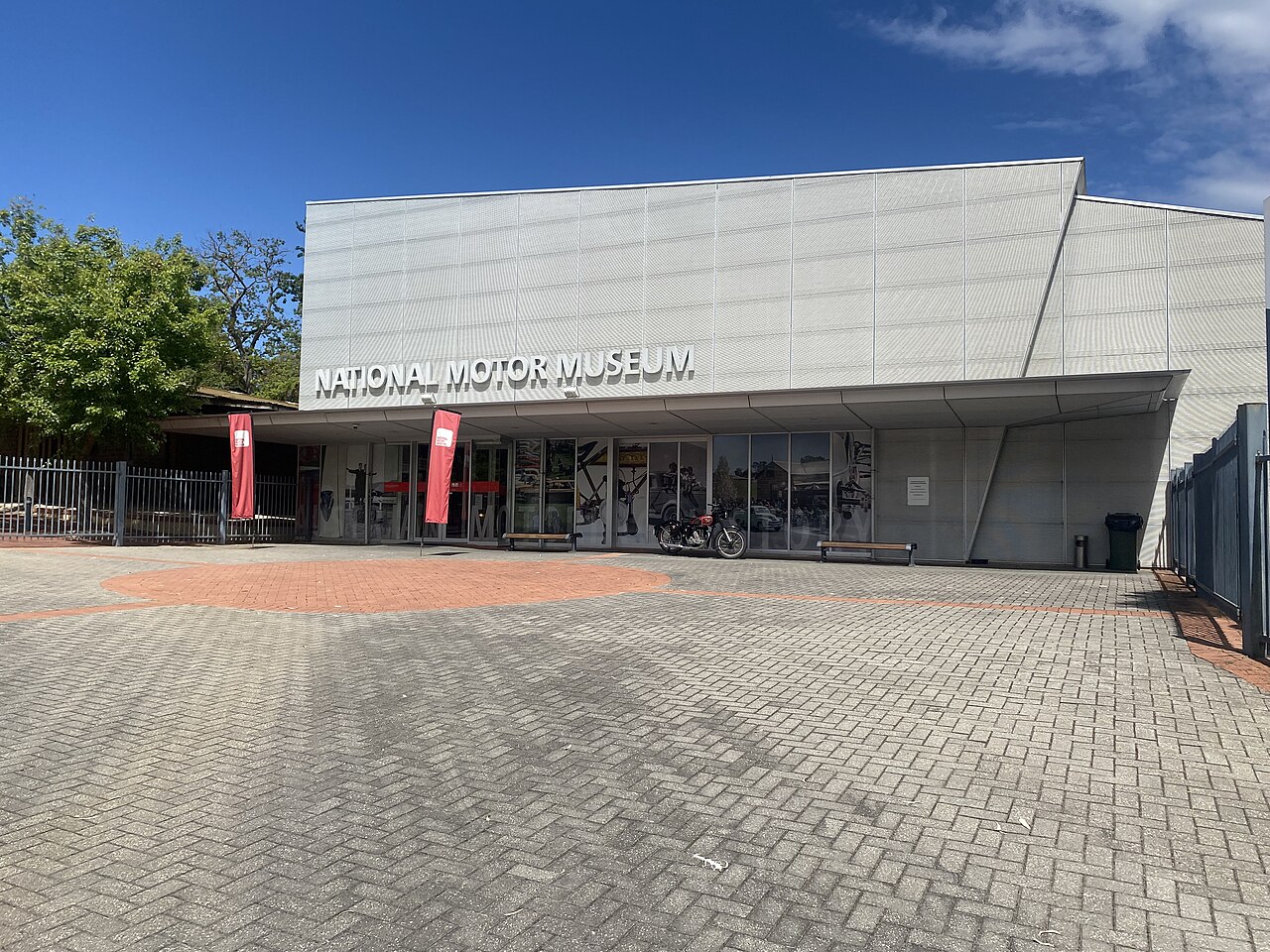 The modern silver entrance building of the National Motor Museum in Birdwood, with its name across the facade and a paved forecourt