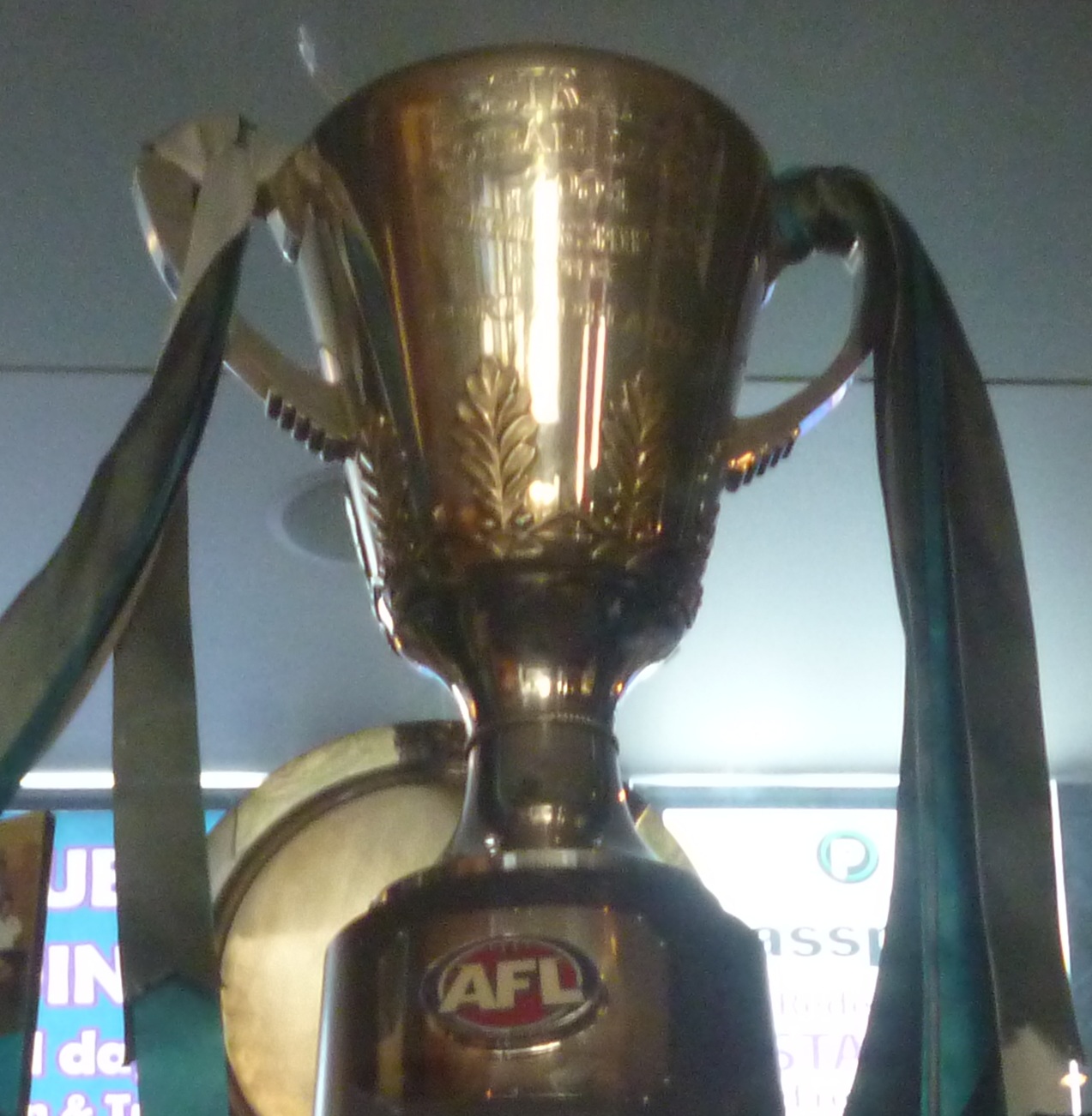 The Port Adelaide 2004 AFL premiership cup, a gold trophy with handles draped in teal and black ribbons